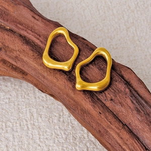 Minimalist irregular molten gold earrings displayed on natural dark wood and beige fabric
