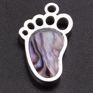 Macro shot of polished stainless steel baby footprint charm with colorful abalone shell inlay