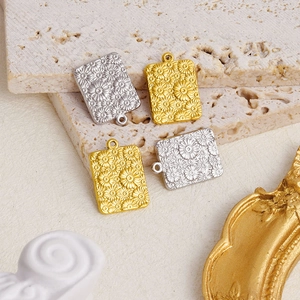 Detail der Gänseblümchen-Reliefanhänger in Gold und Silber auf steinernem Display