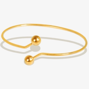 Detailed view of polished 18k gold open cuff bracelet with minimalist metal bead ends