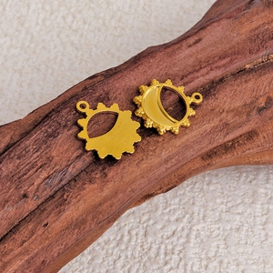 Gold stainless steel sun and moon pendants with textured edges on a rustic wood base