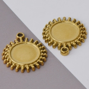 Macro shot of vintage gold sunburst pendant charms with gear edge and hanging loop