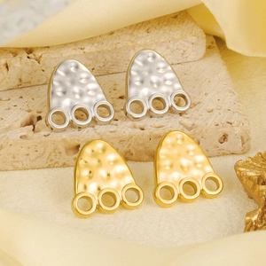 Hammered gold and silver drop earrings with triple ring details on stone surface