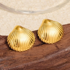 Gros plan sur des boucles d'oreilles coquillage dorées 18k sur bois rustique