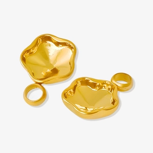 Makroaufnahme unregelmäßiger goldener Metallanhänger mit poliertem Spiegelglanz und Öse
