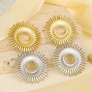 Detailed view of sunburst geometric earrings in gold and silver finish on silk fabric