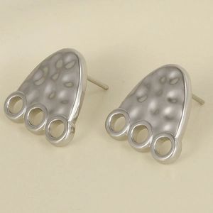 Detail of silver footprint stud earrings with hammered texture and three bottom rings