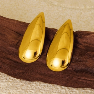 Dettaglio macro di orecchini a goccia in oro lucido con superficie a specchio riflettente