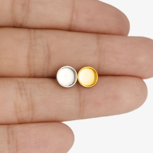 Makroaufnahme von runden Ohrring-Rohlingen aus Edelstahl in Gold und Silber auf einem Finger