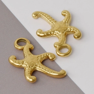 Macro detail of two golden starfish charms with textured surface and circular hanging rings