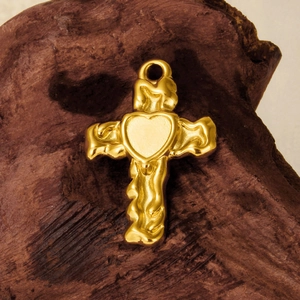 Macro view of gold-plated 304 stainless steel cross pendant with lava texture heart
