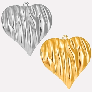 Nahaufnahme von gold- und silbernen Herzanhängern mit zerknitterter Textur für Schmuckdesign