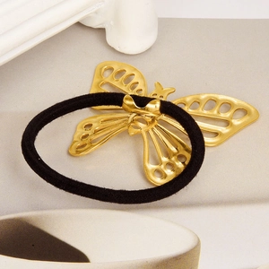 Détail d'un pendentif papillon doré ajouré sur un élastique à cheveux noir robuste