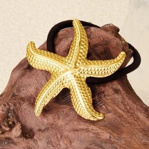 18k gold starfish hair tie with black elastic band on rustic wooden background
