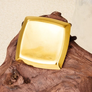 Macro shot of square gold stainless steel hair tie with polished mirror finish on wood