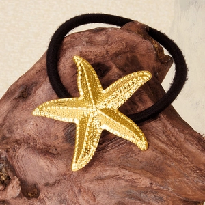 Vue détaillée d'un ornement étoile de mer en or 18 carats sur un élastique à cheveux noir