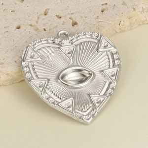 Macro view of polished stainless steel heart pendant with engraved eye motif and sunburst detail