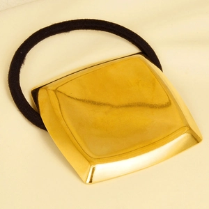 Detail view of square gold polished 304 stainless steel metal cube on a black elastic hair tie