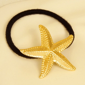 Détail macro d'un élastique à cheveux étoile de mer dorée avec finition texturée