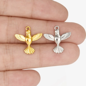 Flying bird pendants in gold and silver steel held by hand for jewelry making