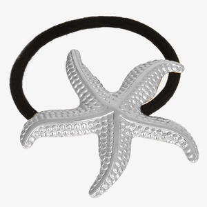 Macro shot of silver starfish pendant with textured surface on black elastic hair tie