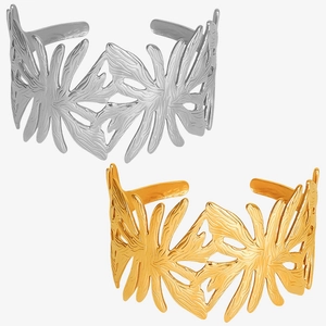 Detail of gold and silver palm leaf open cuff bracelets with intricate metal textures