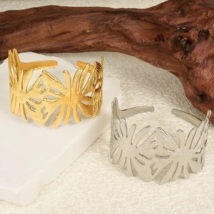 Macro detail of gold and silver open bangles with leaf-inspired hollow texture