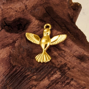 Golden bird pendant made of 304 stainless steel with polished finish on bark background
