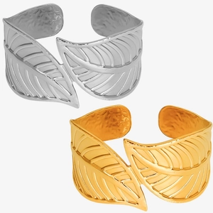 Macro detail of leaf-shaped cuff bracelets in gold and silver showing realistic vein textures