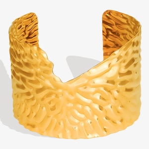 Gros plan d'un bracelet manchette doré 18 carats avec texture martelée en acier inoxydable