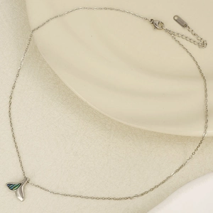 Macro detail of silver fish tail pendant with iridescent abalone shell inlay on steel chain