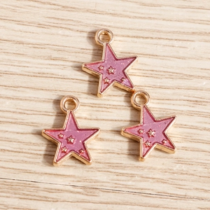 Detailed view of pink enamel star charms with gold trim on a light wood background