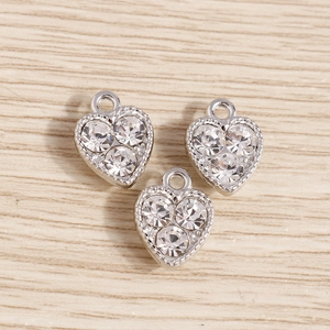 Vue détaillée de breloques en cœur argenté avec trois strass pour bijoux artisanaux