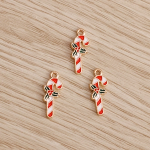 Macro detail of red and white enamel candy cane charms with green holly leaf for DIY jewelry