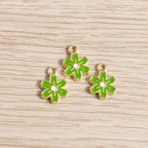 Gros plan de pendentifs fleurs en émail vert avec bordure dorée pour bijoux DIY