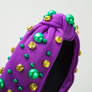 Detail of purple fabric headband featuring green pearls and yellow rhinestones with knot