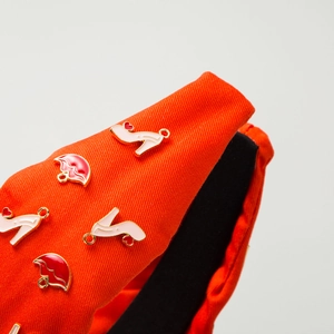 Détail d'un serre-tête orange avec des breloques en émail de talons et de lèvres