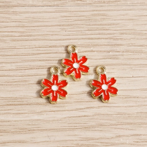 Détail macro de pendentifs fleurs en émail rouge et alliage doré pour bijoux DIY