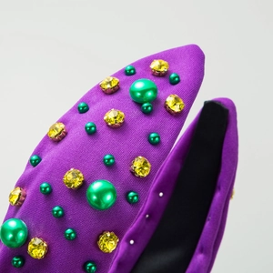 Detail of purple knotted headband with green faux pearls and yellow rhinestones