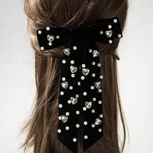Détail du nœud de cheveux en velours noir avec strass cœur et perles sur les cheveux