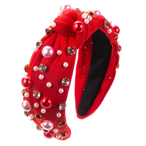Detailed view of red knotted headband featuring imitation pearls and sparkling rhinestones
