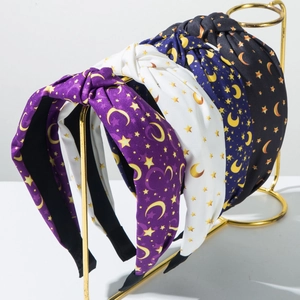 Set of four knotted fabric headbands featuring gold star and moon prints on a metal stand