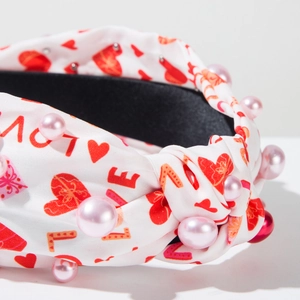 Détail du serre-tête noué blanc avec motifs cœurs, imprimé LOVE et perles roses
