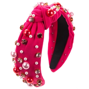 Detailed close-up of a magenta knot headband featuring shiny pearls and colorful rhinestones