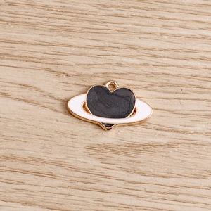 Dettaglio di un ciondolo cuore a forma di pianeta con smalto nero e bordo in metallo dorato
