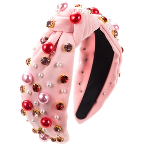 Detail of pink knotted headband featuring red rhinestones and white pearls on fabric