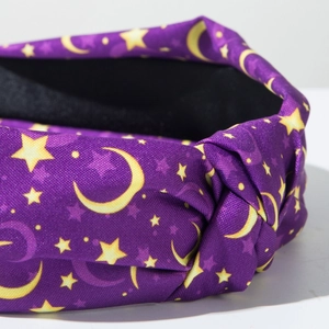 Close-up of purple knotted headband featuring yellow stars and moon fabric texture