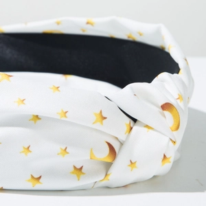 Detail of fabric knotted headband with golden star and moon prints on white silk texture