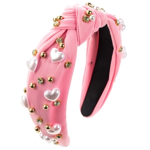 Close-up of pink knotted headband with heart-shaped pearls and sparkling rhinestones