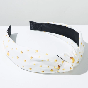 Detail of white knotted headband with gold star and moon print on a clean background
